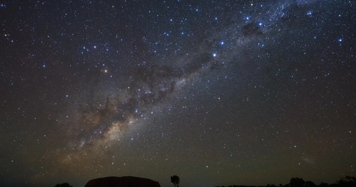The Milky Way over the dark park, with a faint rock outline on the horizon