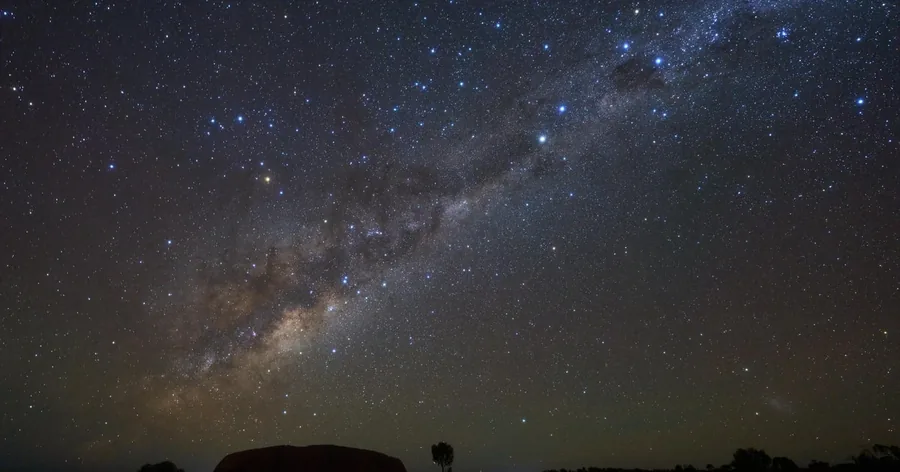 The Milky Way arching over the dark national park, the outline of the land on the horizon